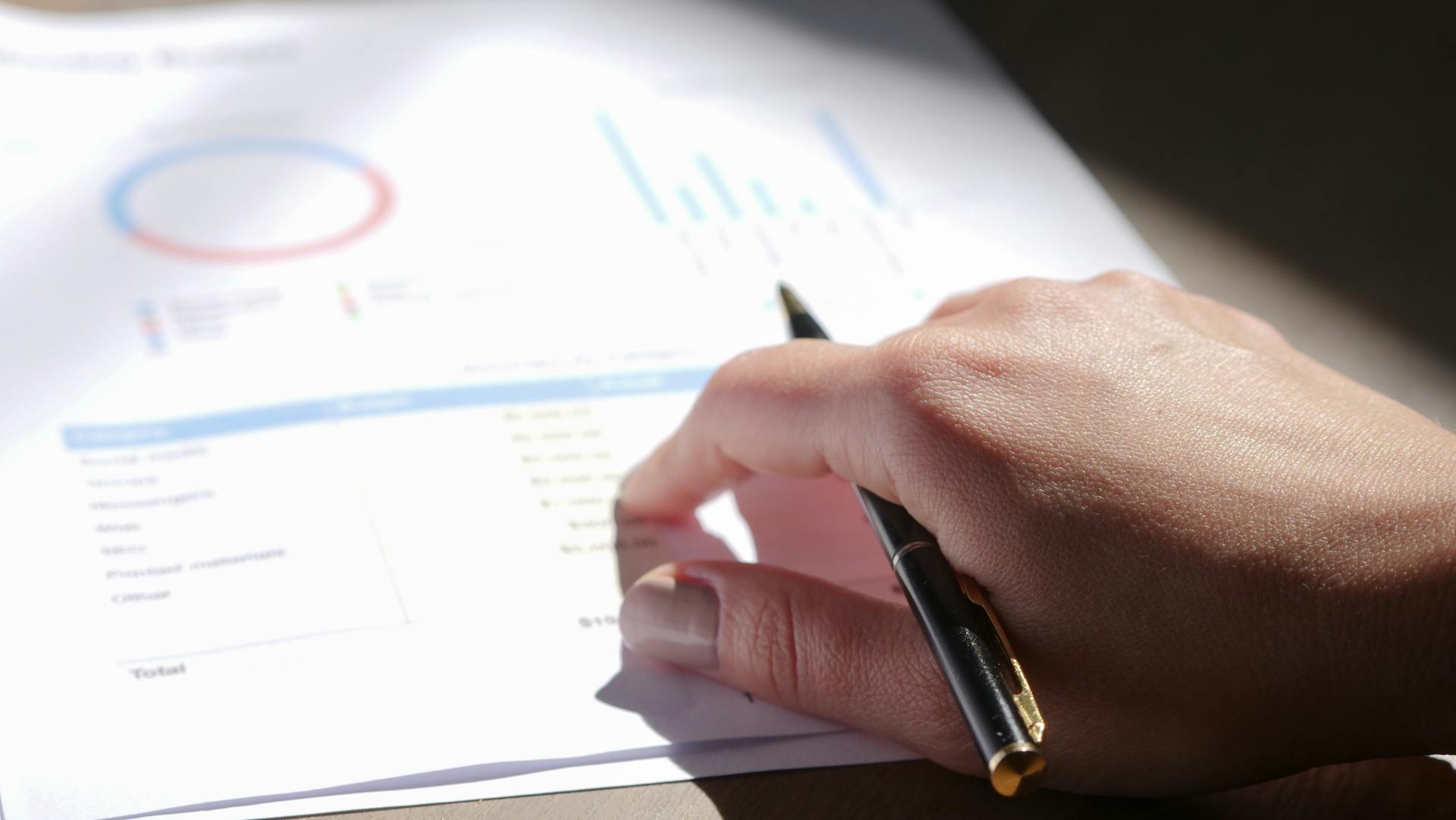 Business owner reviewing financial reports and charts on paper at a desk.