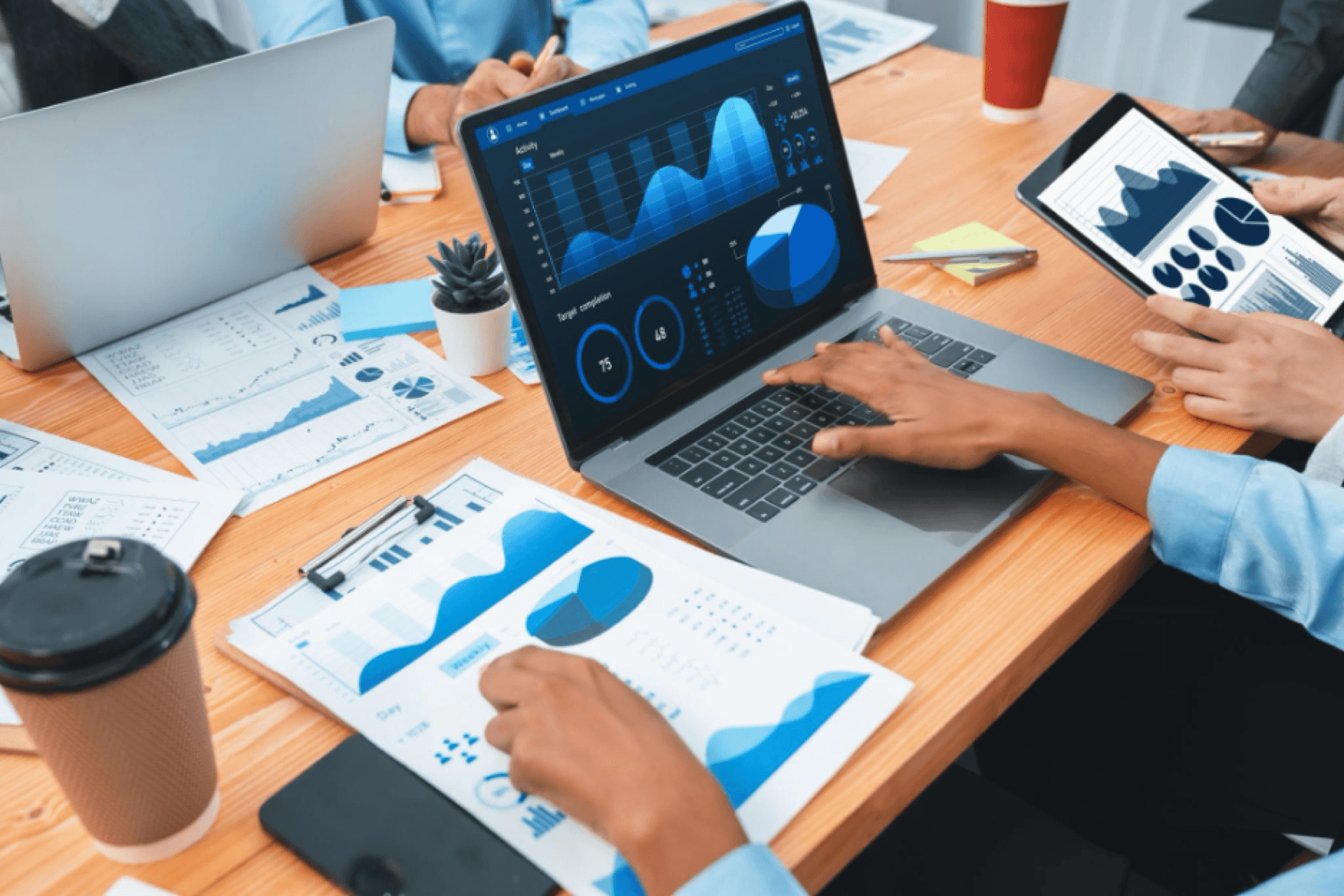 Team reviewing financial dashboards, charts, and analytics on laptops and tablets at a desk