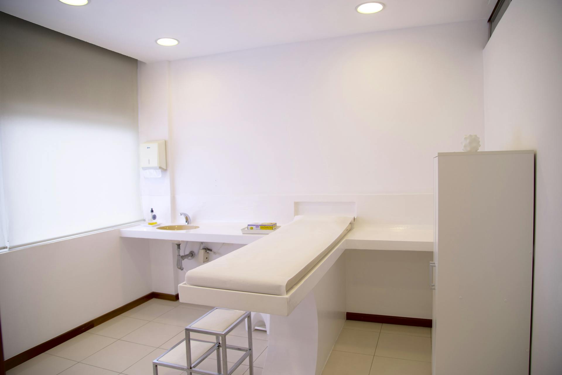 Modern aesthetic clinic treatment room with clean white interior and examination table.