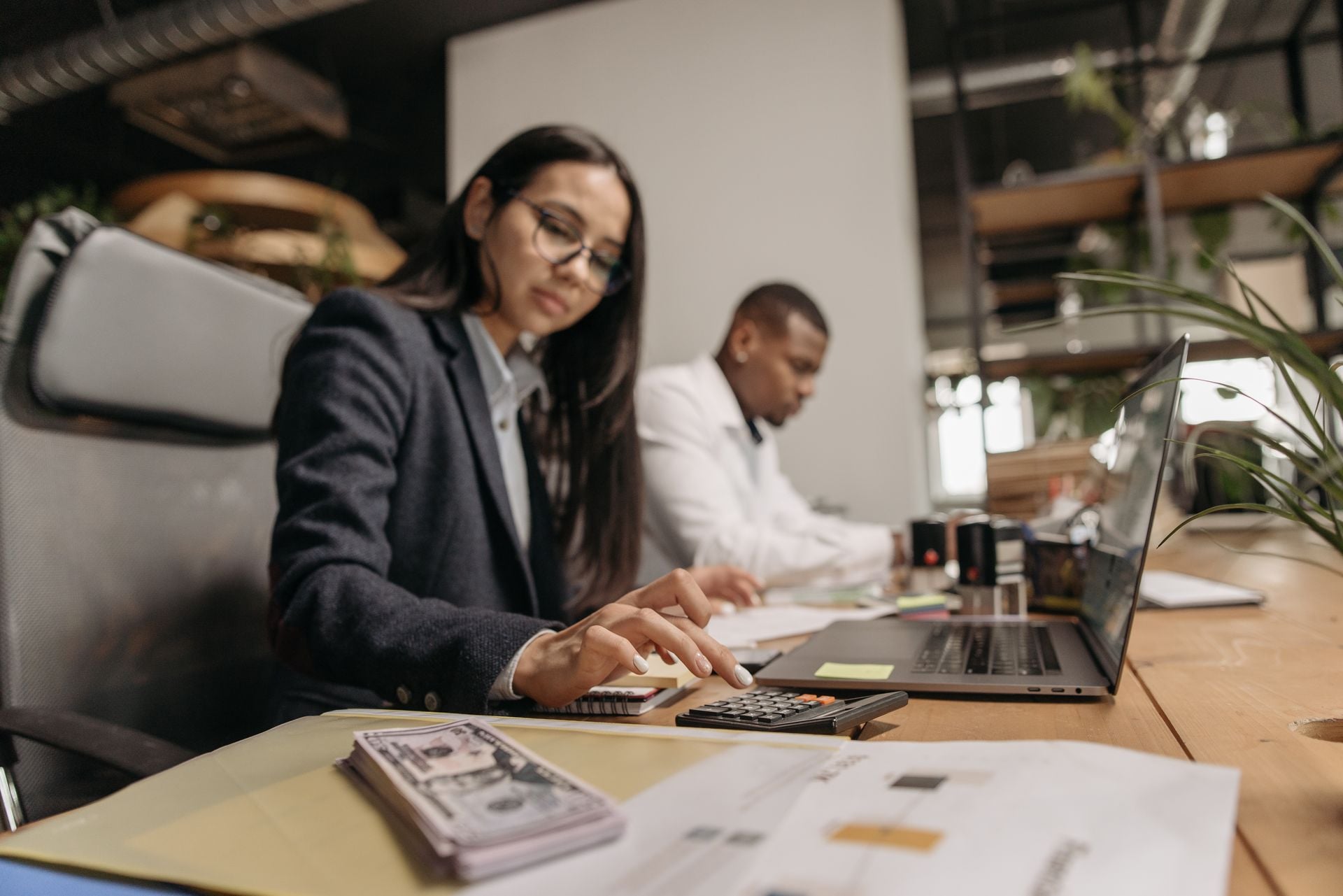 Med spa owner reviewing finances with calculator, cash, and documents at a desk